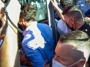 Des rochers frappent le premier ministre Justin Trudeau dans le dos alors qu'il monte à bord de son autobus à la fin d'un arrêt de campagne à Londres, en Ontario, le 6 septembre 2021.