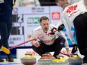 Le capitaine canadien Brad Gushue crie au deuxième EJHarnden, à droite, et au premier Geoff Walker alors qu'ils balayent une pierre du troisième Mark Nichols dans la maison au quatrième bout du match de vendredi soir contre la Suède.