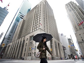 Une femme passe devant des édifices bancaires à Toronto.