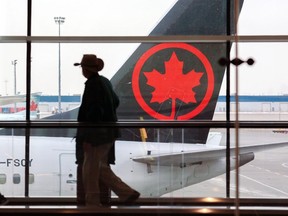 Les voyageurs se déplacent entre les portes avec un avion d'Air Canada en arrière-plan à l'aéroport international de Calgary le mardi 18 janvier 2022.