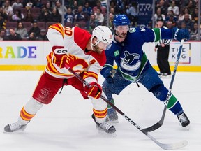 Le défenseur des Canucks de Vancouver Kyle Burroughs se défend contre l'attaquant des Flames de Calgary Jonathan Huberdeau en deuxième période au Rogers Arena.