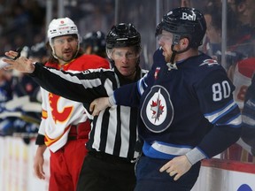 Un juge de lignes sépare Pierre-Luc Dubois des Jets de Winnipeg et Chris Tanev des Flames de Calgary en deuxième période lors d'un match le 5 avril 2023 au Canada Life Centre de Winnipeg.