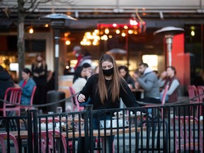 Un serveur débarrasse une table sur une terrasse dans un restaurant, à Vancouver.