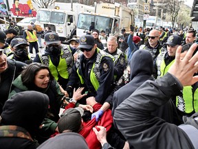 La police de Vancouver repousse les manifestants alors que le personnel de la ville enlève les structures de fortune et les tentes appartenant aux personnes vivant dans un campement le long de la rue East Hastings dans le Downtown Eastside, à Vancouver, en Colombie-Britannique, le 5 avril 2023.