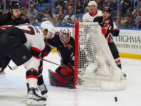 Le gardien de but des Sabres et ancien sénateur Craig Anderson et Mark Kastelic d'Ottawa regardent la rondelle rouler près de l'enclave lors de la première période du match de jeudi à Buffalo.