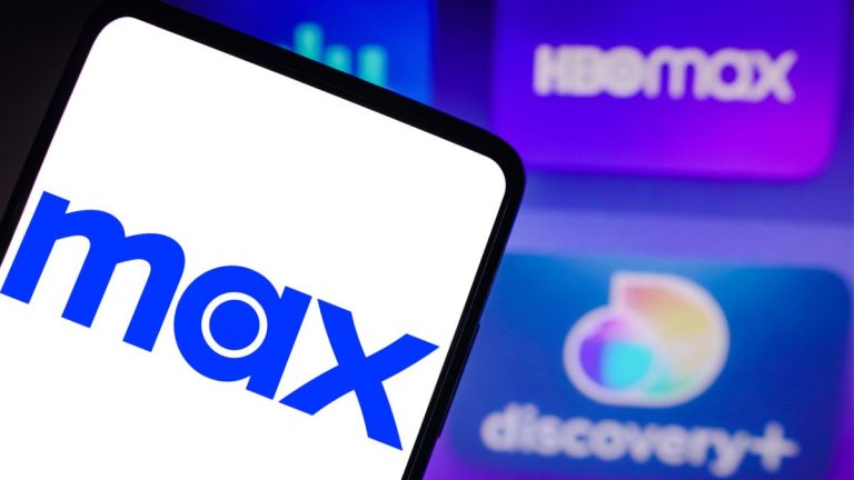 In this photo illustration, the Max logo is seen displayed on a smartphone, the HBO Max and Discovery+ logo in the background.