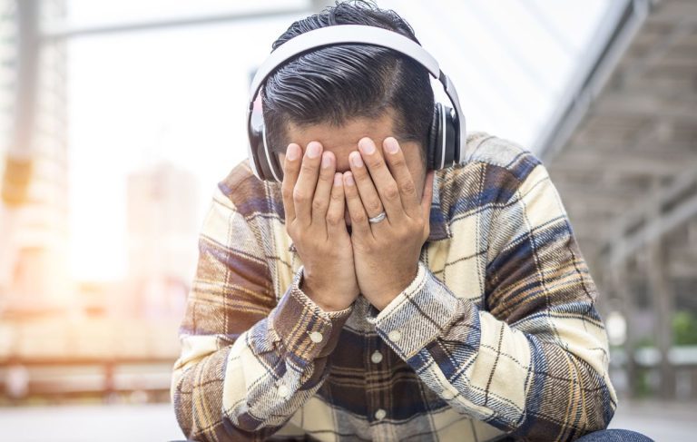 Person covering face while wearing headphones