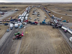 Des manifestants anti-mandat se rassemblent alors qu'un convoi de camions bloque l'autoroute du passage frontalier américain très fréquenté à Coutts, en Alberta, le lundi 31 janvier 2022.