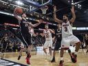 Mitch Wood, des Ravens de Carleton, à gauche, cherche à passer avant de sortir des limites devant Noah Daoust, au centre, des Redmen de McGill, et Dele Ogundokun lors du match pour la médaille de bronze du championnat national de basketball masculin U Sports à Halifax le dimanche 11 mars. 2018.