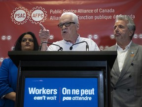 La vice-présidente exécutive nationale de l'Alliance de la Fonction publique du Canada, Sharon DeSousa, à gauche, et le vice-président exécutif régional du Québec, Yvon Barriere, regardent le président national Chris Aylward faire un point lors d'une conférence de presse au siège social du syndicat à Ottawa.