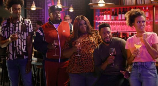 Five adults holding glasses of wine at a bar and looking at something O.S.; still from "Grand Crew"