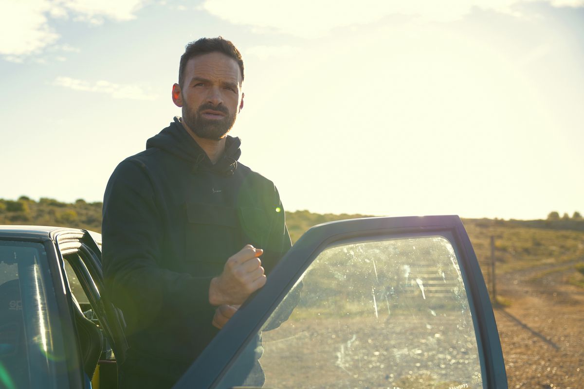 Alban Lenoir fait un poing avec sa main sur une portière de voiture ouverte dans Lost Bullet 2