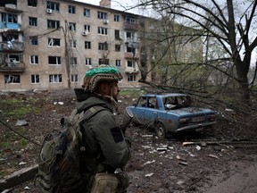 Un militaire ukrainien marche près d'un immeuble résidentiel endommagé par des bombardements dans la ville de Bakhmut, en première ligne, le 23 avril.