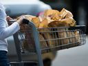 Une femme quitte une épicerie avec des sacs en plastique à Mississauga, en Ontario, le jeudi 15 août 2019. LA PRESSE CANADIENNE/Nathan Denette 