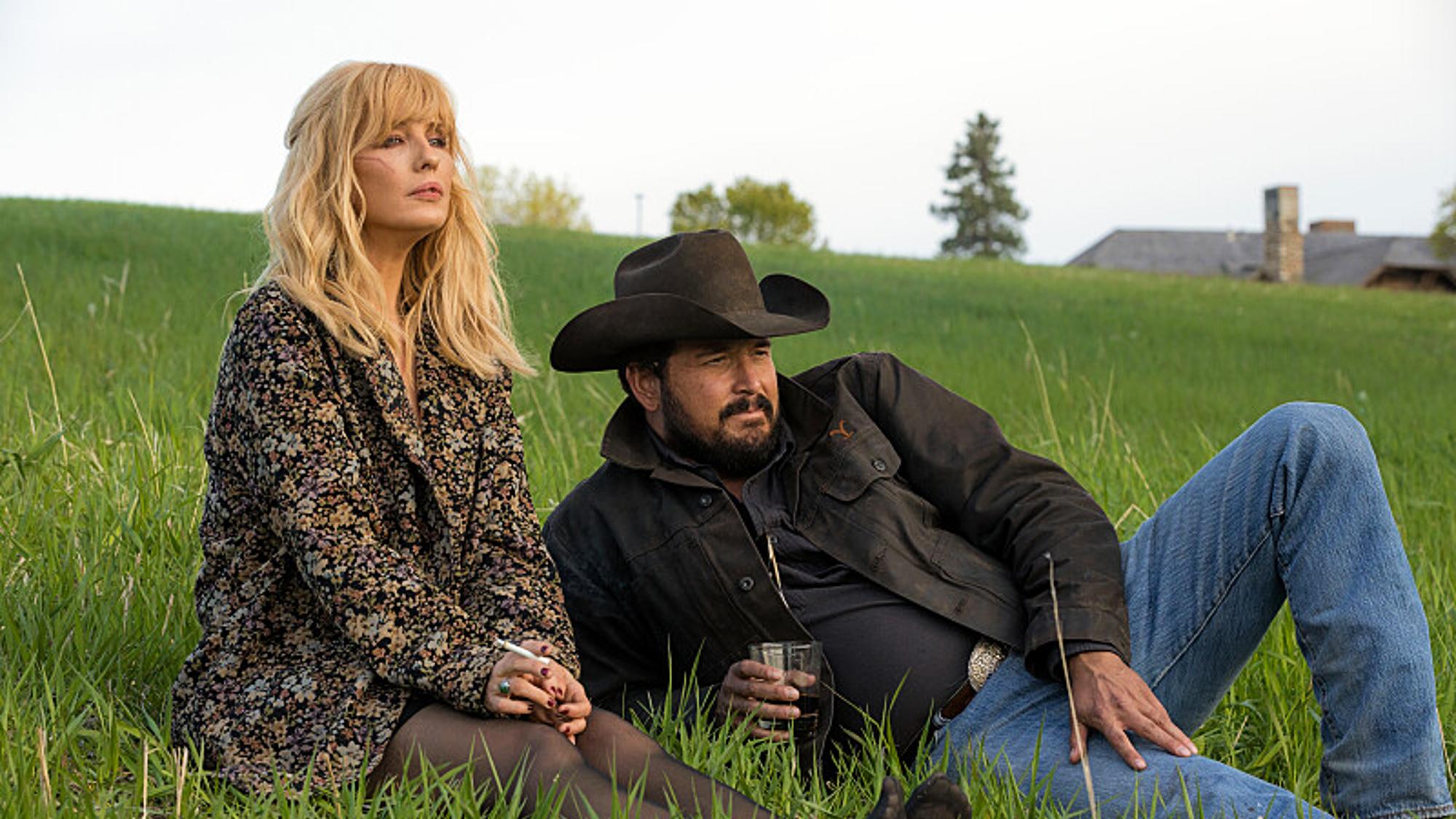 Kelly Reilly dans le rôle de Beth Dutton et Cole Hauser dans le rôle de Rip Wheeler sont assis dans l'herbe lors de la saison 5 de Yellowstone