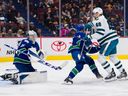 Le gardien des Canucks de Vancouver Thatcher Demko effectue un arrêt alors que le défenseur Kyle Burroughs se bat avec l'attaquant des Sharks de San Jose Tomas Hertl en deuxième période au Rogers Arena le 23 mars 2023.