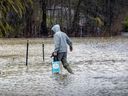 Un homme transporte des provisions à son domicile dans une rue inondée alors que la rivière des Outaouais déborde de son lit à Rigaud, à l'ouest de Montréal, le lundi 1er mai 2023.