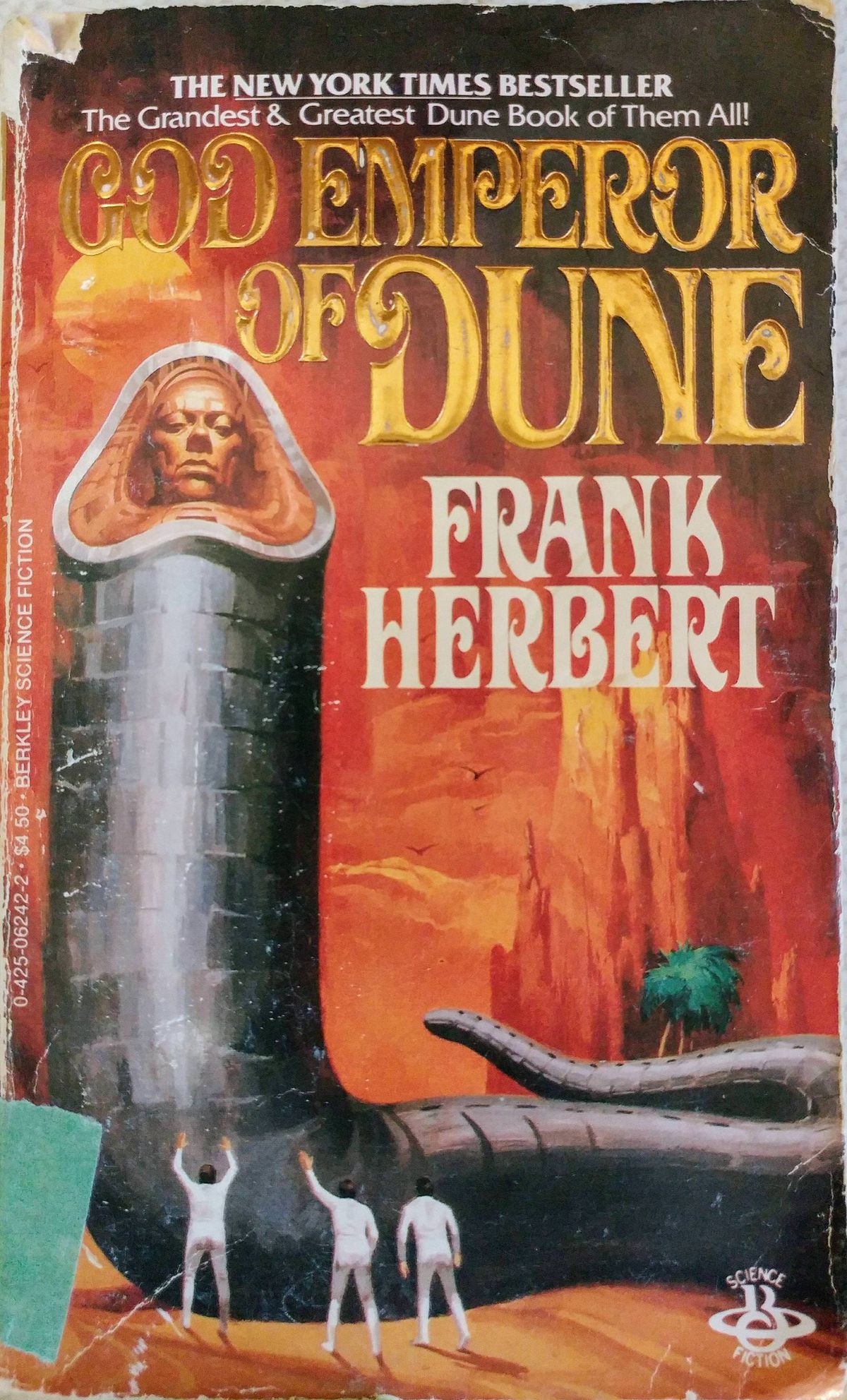 La couverture de 1984 des Berkley Books de God Emperor of Dune , avec trois hommes en blanc debout à la base d'une imposante figure grise en forme de ver à l'échelle avec un visage humain où sa bouche serait