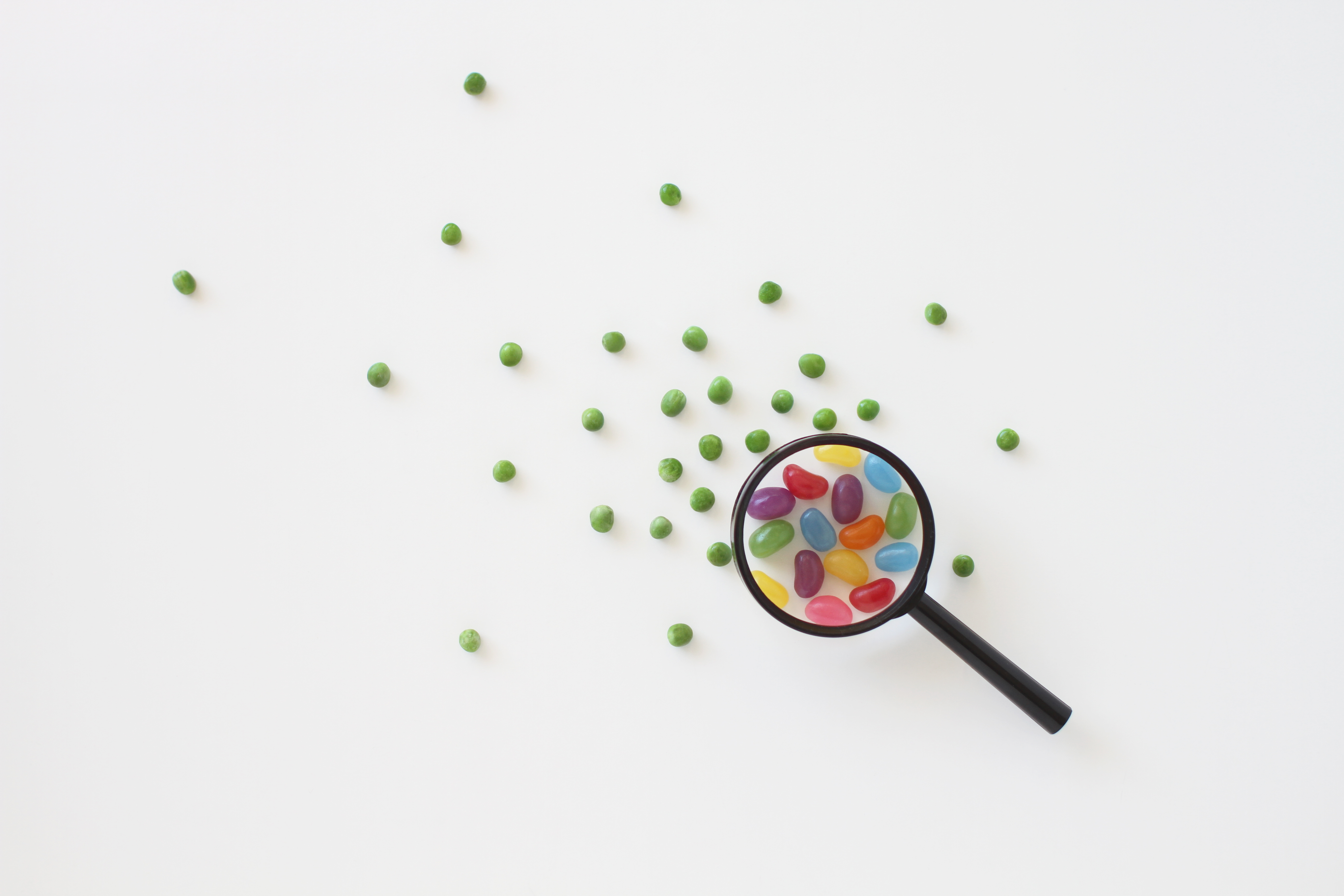 Image de bonbons sous une loupe entourée de pois pour représenter l'examen réglementaire.