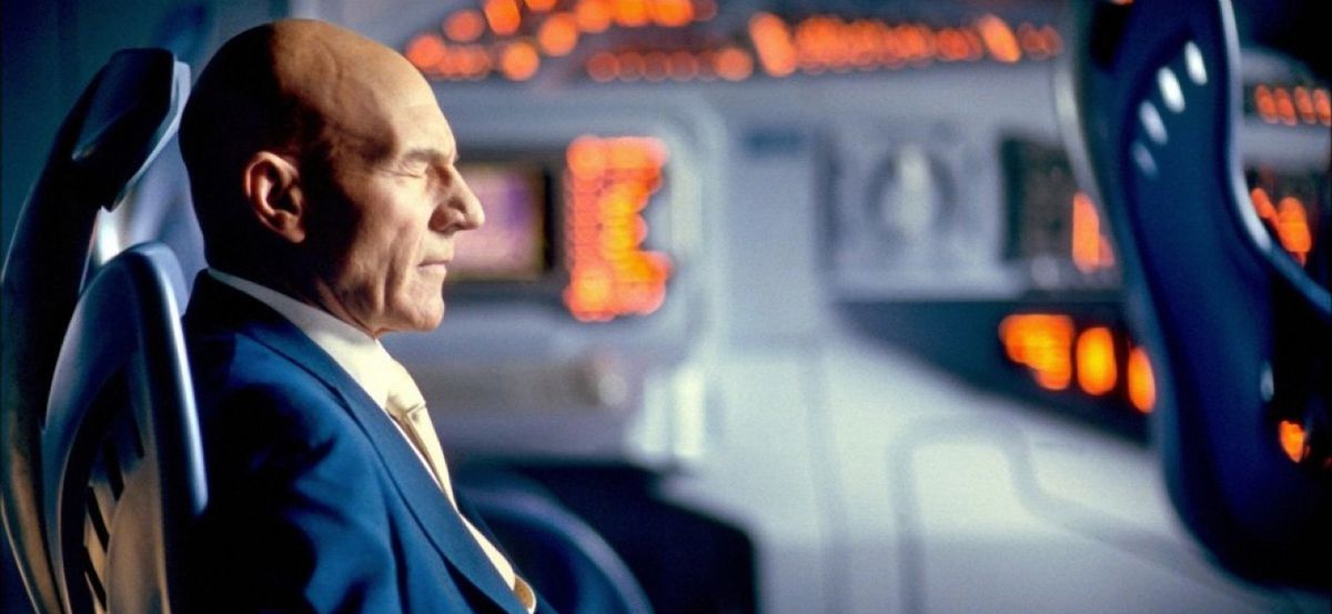 Le professeur X (Patrick Stewart) est assis les yeux fermés, entouré de sièges bleus et de lumières oranges, dans X2 : X-Men United