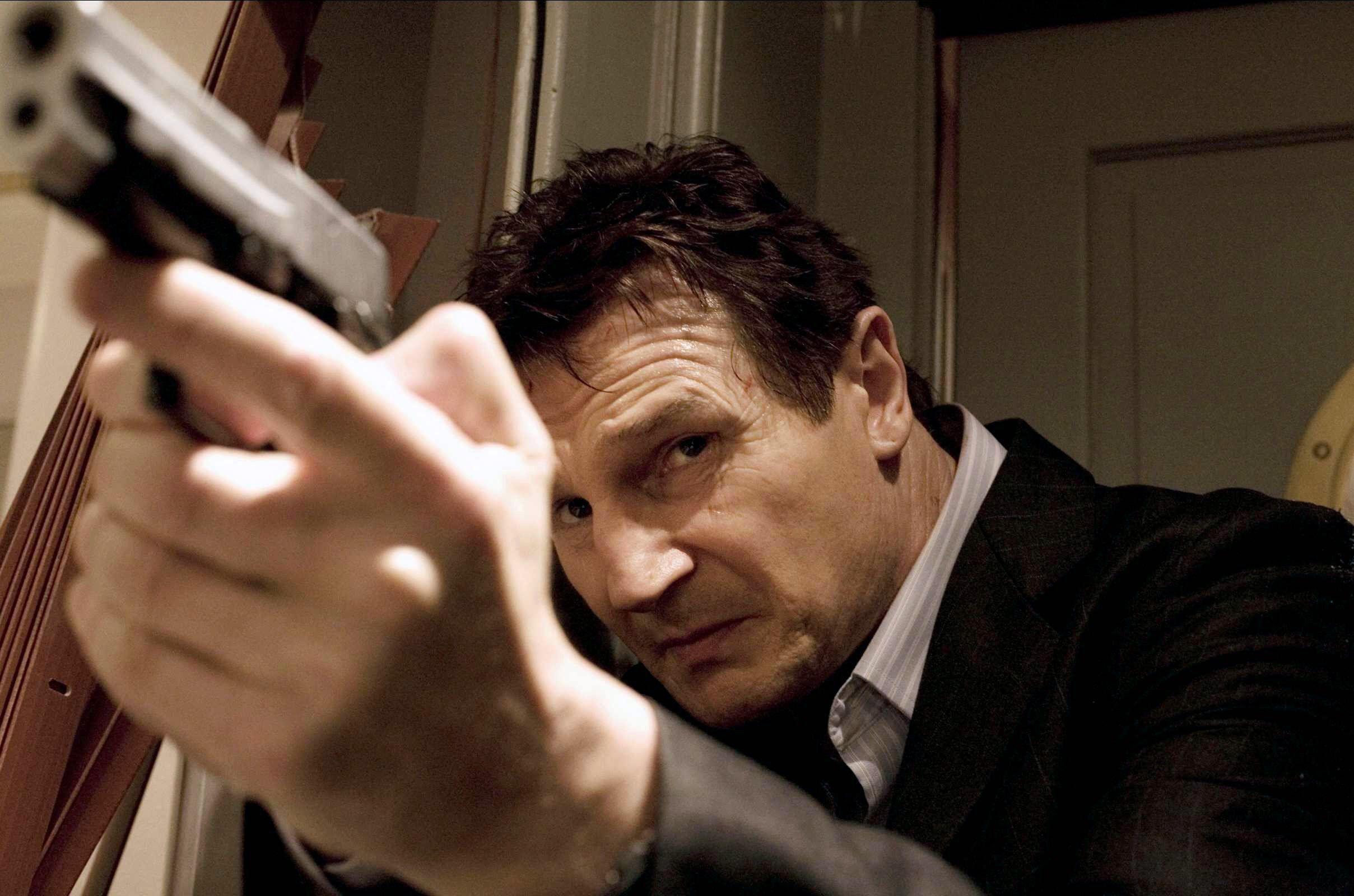 Liam Neeson pointe une arme vers le haut dans Taken