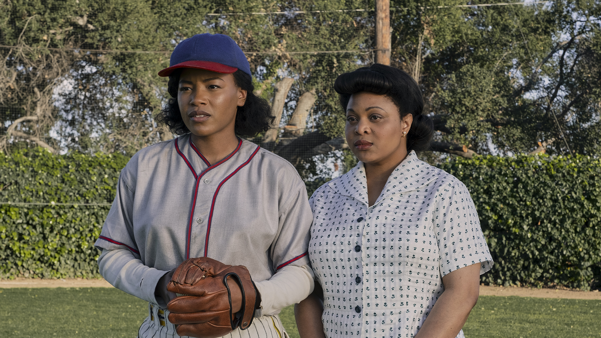 (L à R) Chanté Adams (Max) est dans son uniforme de baseball tenant un gant tandis que Gbemisola Ikumelo (Clance) se tient à ses côtés tenant un sac à deux mains dans A League of Their Own