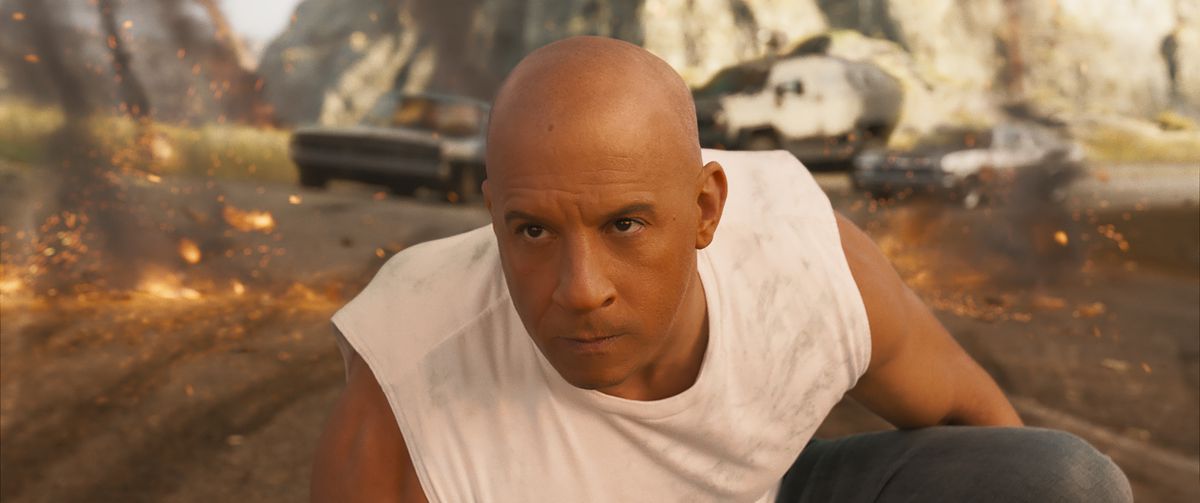 Dom (Vin Diesel) s'accroupit sur un genou alors que des débris de voiture explosent autour de lui en F9