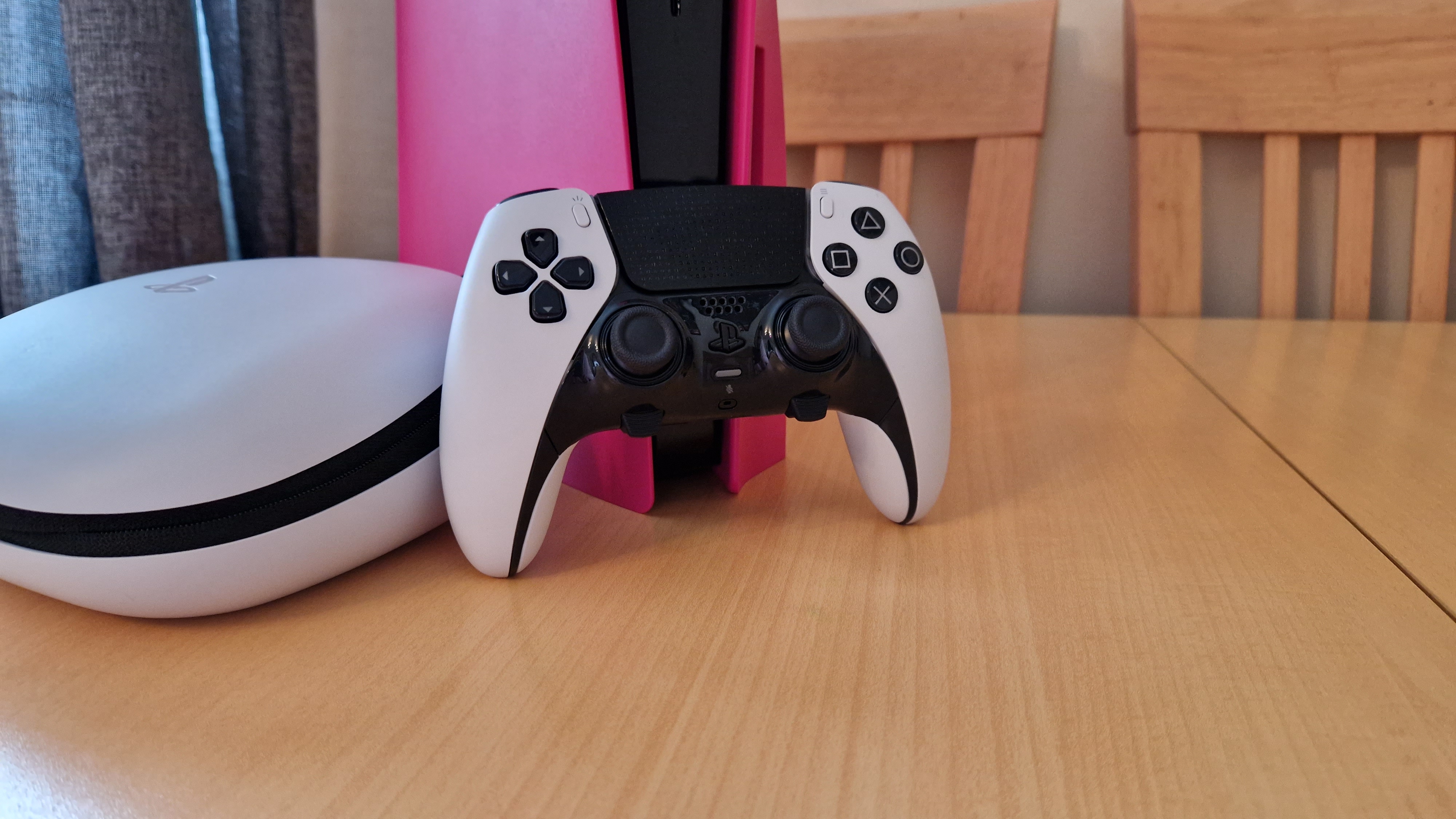 Image de revue DualSense Edge montrant le contrôleur debout contre une PS5 rose