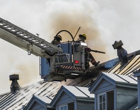 Des pompiers au bout d'un camion-échelle combattent un incendie sur le toit d'un immeuble ancien