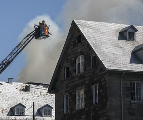 Des pompiers au bout d'un camion-échelle combattent un incendie sur le toit d'un immeuble ancien