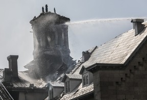 Les pompiers à la fin d'un camion à échelle pulvérisent le toit d'un immeuble en feu