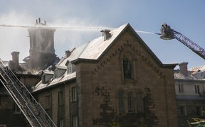 Les pompiers à la fin d'un camion à échelle pulvérisent le toit d'un immeuble en feu