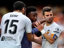 Vinicius Junior du Real Madrid fait des gestes vers un fan alors que Jose Gaya et Cenk Ozkacar de Valence tentent de le retenir.