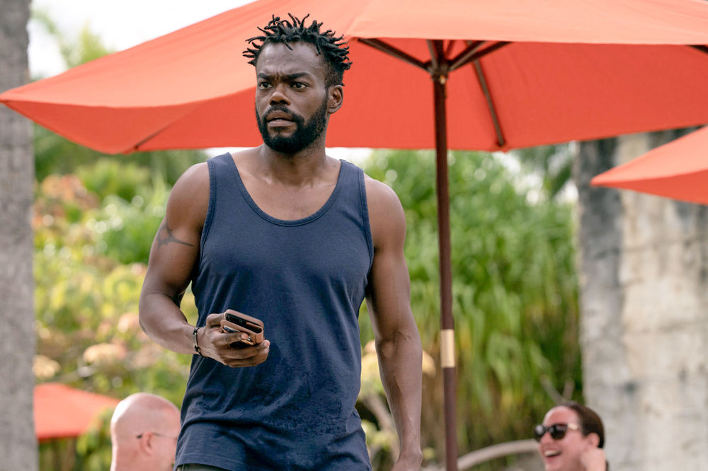 William Jackson Harper dans le rôle de Noah, tenant son téléphone au bord de la piscine, dans The Resort