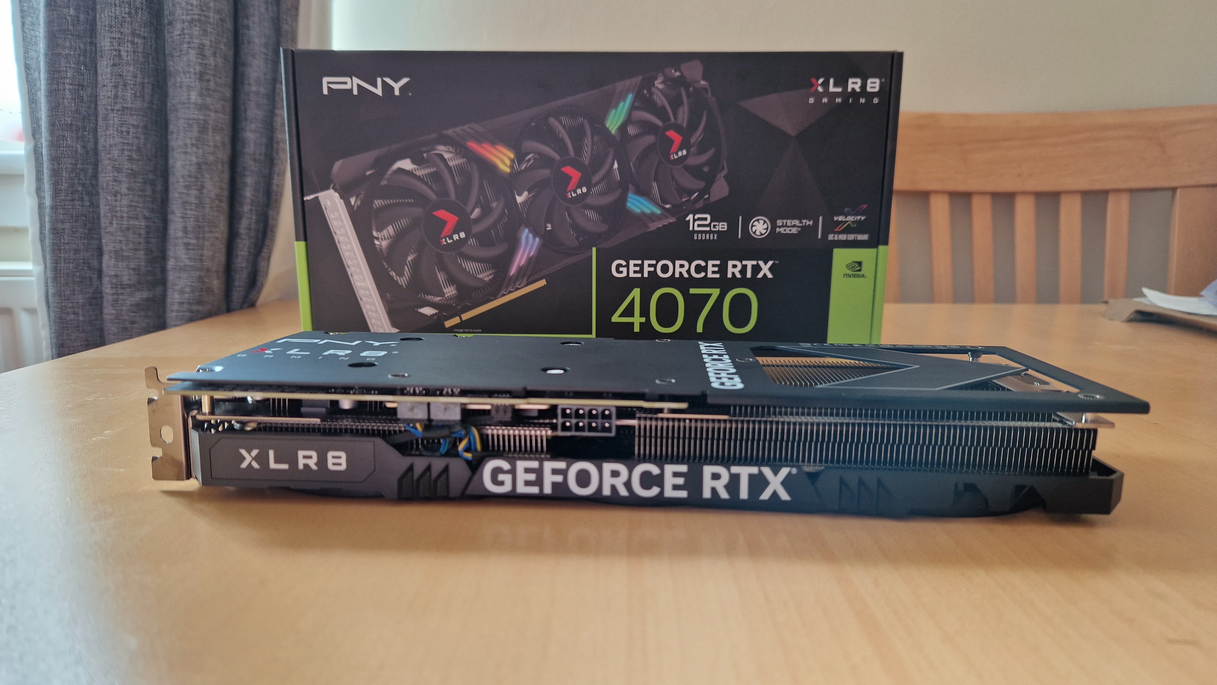 PNY GeForce RTX 4070 posée à l'horizontal sur une table devant sa boite