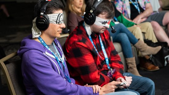 SGDQ 2023 - deux speedrunners sont assis côte à côte avec les yeux bandés, partageant un contrôleur entre eux.