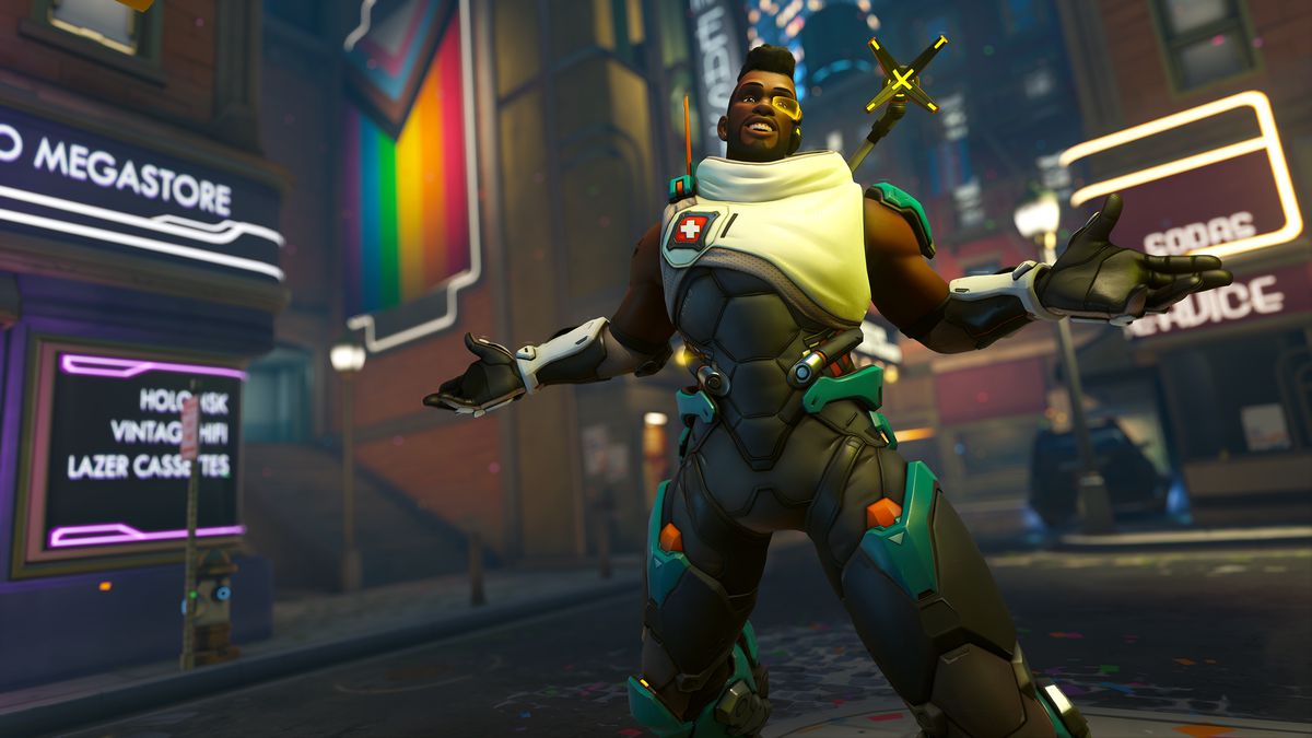 Baptiste pose avec un drapeau Pride sur une version nocturne de la carte Midtown (New York) d'Overwatch 2.