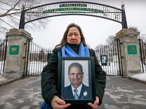 Evanthia Karassavidis tient une photo de son défunt père, Logothetis, devant les portes verrouillées du cimetière Notre-Dame-des-Neiges à Montréal le jeudi 16 mars 2023. Son père est décédé en février, mais son corps ne peut être enterré à cause de une grève au cimetière.