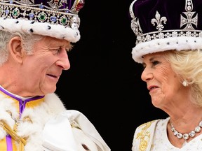 Le roi britannique Charles III (L) regarde la reine Camilla alors qu'ils se tiennent sur le balcon du palais de Buckingham, à Londres, après leurs couronnements, le 6 mai 2023.