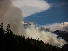 Un hélicoptère transportant un seau d'eau survole le feu de forêt de Lytton Creek qui brûle dans les montagnes près de Lytton, en Colombie-Britannique, le dimanche 15 août 2021. Deux incendies de forêt incontrôlables dans le nord-est de la Colombie-Britannique qui ont déjà forcé certains résidents à évacuer leur On s'attend à ce que les maisons s'agrandissent dans les prochains jours.