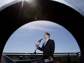 Pierre Poilievre, chef du Parti conservateur du Canada et de l'Opposition officielle, est encadré par l'accoudoir d'un banc de parc alors qu'il s'adresse aux médias lors d'un arrêt à Edmonton, le jeudi 13 avril 2023.