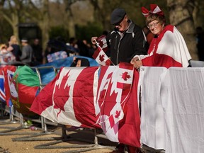 Bernadette Christie, à droite, et son mari Bruce Christie de Grand Prairie, en Alberta, accrochent leurs drapeaux canadiens le long de la clôture où elle et son mari campent quelques jours avant le couronnement officiel du roi Charles III près du palais de Buckingham le long du Mall à Londres, Mercredi 3 mai 2023.