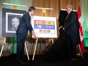 Le drapeau royal est dévoilé par Samy Khalid, à gauche, héraut en chef du Canada à l'Autorité héraldique du Canada et Donald Booth, secrétaire canadien du roi lors des célébrations du couronnement en l'honneur du roi Charles III à Ottawa, le samedi 6 mai 2023.