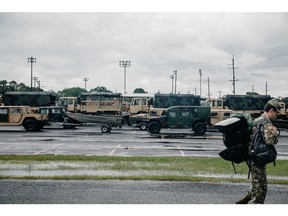 Un soldat de la Garde nationale de l'armée de Louisiane passe devant des véhicules à roues polyvalents à haute mobilité (Humvees) et des bateaux de sauvetage devant l'ouragan Laura à Lake Charles, Louisiane, États-Unis, le mercredi 26 août 2020. Les petits réacteurs de BWX pourraient être utilisés pour aider alimenter les efforts de secours en cas de catastrophe.  Photographe : Bryan Tarnowski/Bloomberg