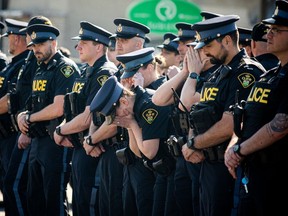 Certains policiers qui montent la garde sont submergés par l'émotion alors que le cercueil du sergent de la Police provinciale de l'Ontario.  Eric Mueller est amené au salon funéraire Brunet à Rockland samedi.  Mueller est décédé après avoir été abattu à Bourget, à l'est d'Ottawa, tôt jeudi.