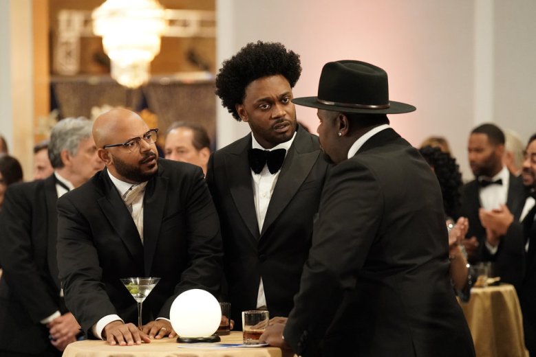 Trois hommes en smoking, l'un portant un chapeau et debout à une table de cocktail ;  encore de 