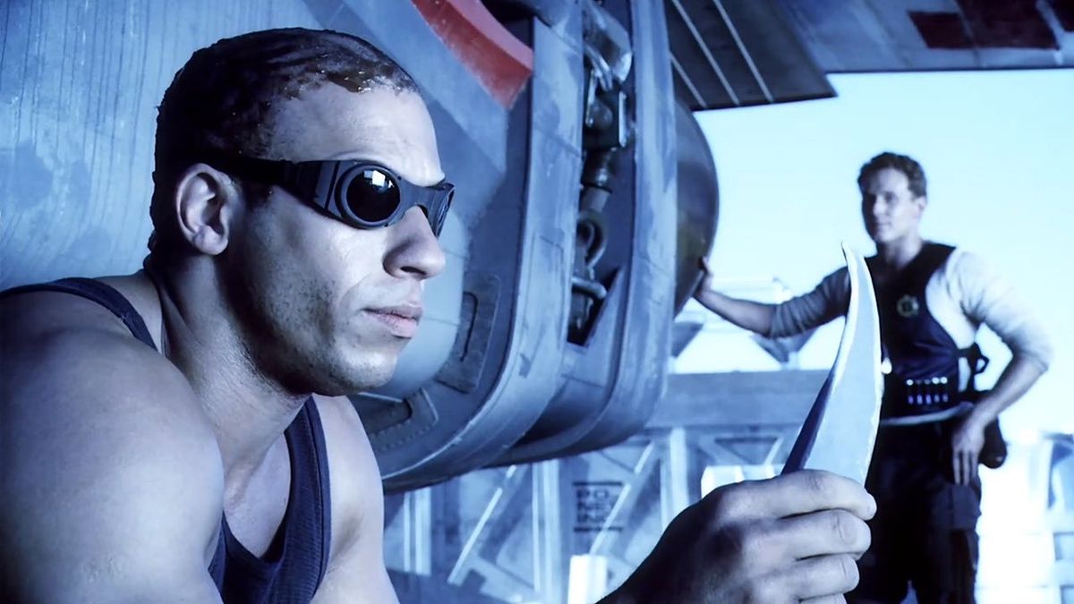 (LR) Richard B. Riddick (Vin Diesel) fixant un couteau avec William J. Johns (Cole Hauser) en arrière-plan dans Pitch Black.