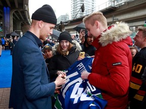 Elias Pettersson des Canucks de Vancouver rencontre des partisans avant son match de la LNH contre Calgary au Rogers Arena le 8 avril à Vancouver.