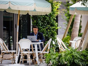 Un client travaille sur un ordinateur portable dans la salle à manger extérieure du restaurant Pura Vida sur Rosemary Avenue à West Palm Beach, en Floride.