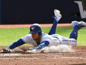 Le voltigeur droit des Blue Jays George Springer glisse sur le marbre alors qu'il marque un point contre les Braves lors de la septième manche au Rogers Centre de Toronto, le samedi 13 mai 2023.